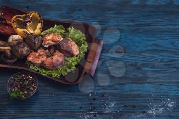 Grilled pork meat with vegetable on a blue wooden background