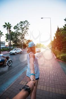Beauty woman in blue hat holding man by hand and going around the Alanya city in Turkey
