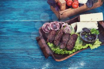 Grilled lula kebab - meat dish, with vegetable on a blue wooden background