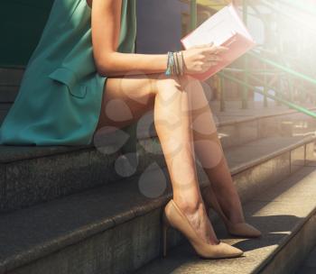 Close up of woman with beauty leg holding a book on the street