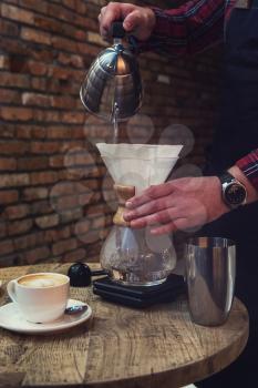 Barista brewing coffee in chemex in the cafe
