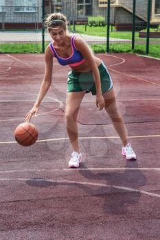 A young beauty athletic woman in sportswear with basketball ball