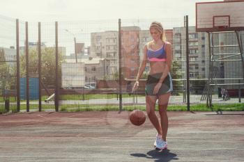 A young beauty athletic woman in sportswear with basketball ball