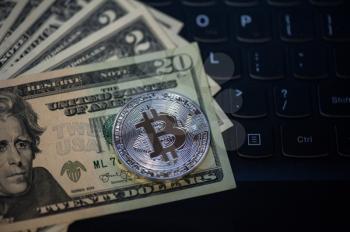 Bitcoin coin with dollars on the laptop background
