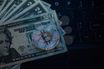Bitcoin coin with dollars on the laptop background