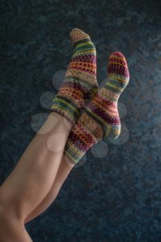 Woman legs in wool knitted socks on a grey background