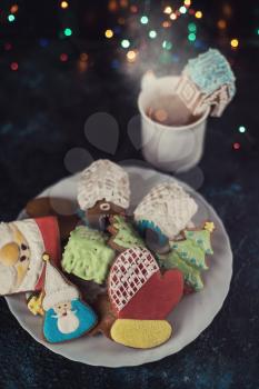 Christmas cookies and cup of tea on dark color bokeh lights background