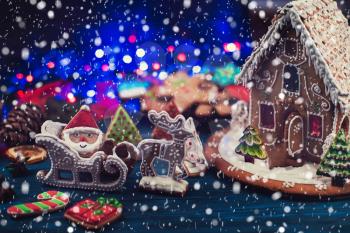Gingerbread house and figures with lights on dark background, xmas theme