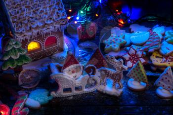 Gingerbread house and cookie figures with lights on dark background, xmas theme