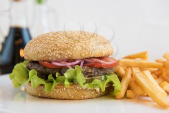Tasty classical burger with fried potato on white table