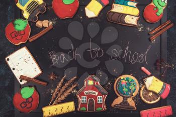 Concept photo of Back to school with gingerbreads cookies on a dark background with school board