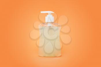Cosmetic bottles of cream, soaps, foams, or shampoo on orange background.