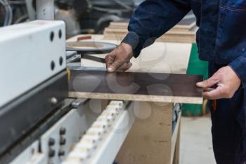 Furniture production or craft concept: worker making the wood surface of furniture part with special machine