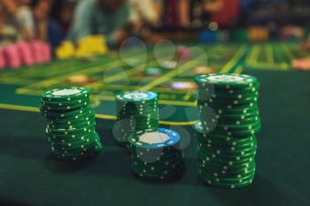 Casino, gambling and entertainment concept - stack of poker chips on a green table