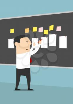 Businessman pinning sheets of paper and stickers on blackboard with concentrated or serious facial expression. Manager making business plan or reaching goal, setting task or posing problem. 