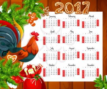 Christmas calendar on wooden background. Year calendar with xmas tree, gift box, candy cane, holly berry, chinese zodiac rooster, gingerbread and bauble ball. Festive New Year calendar design