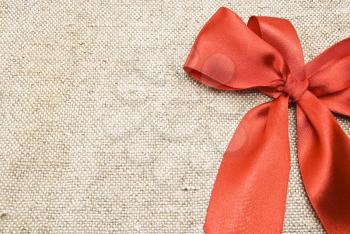 Royalty Free Photo of a Red Bow on a Sackcloth Background