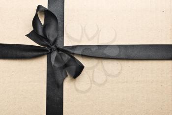 Royalty Free Photo of Black Satin Ribbon and Bow on a Cardboard Background