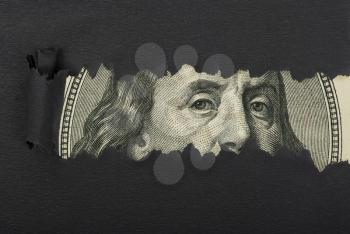 Benjamin Franklin macro peeking through torn black paper