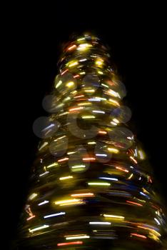 Blurred rotating New Year tree at night over black