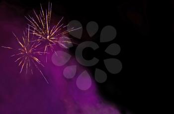 Bright Fireworks in lilac smoke at night in the black sky useful as holiday background