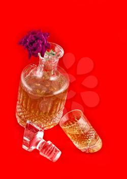 Crystal decanter with jigger for alcoholic beverage and flower over red background