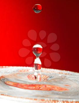 Extreme close-up. Falling drops of water over red. 