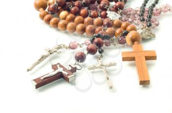 Diversity of Religion - rosary beads over white with focus on crosses (shallow DOF)