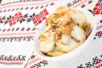 Ukrainian dishes - dumplings with fried onion on traditional embroidered towel