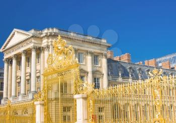 Versailles Palace facade and golden fence over blue sky. France