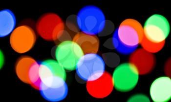 Blurred colorful festive lights at night useful as background over black 