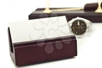 Card holder with blank white business card, watch, and pens on stand on the background over white