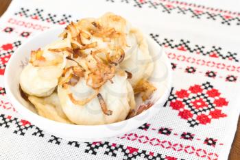 Ukrainian dumplings with fried onion on traditional embroidered towel