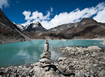 Balance: Stone stack and Sacred Lake near Gokyo in Himalayas