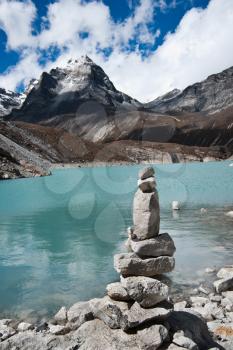 Harmony: Stone stack and Sacred Lake near Gokyo. Travel to Nepal