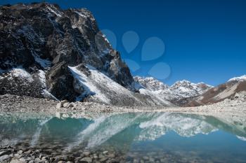 Mountain peaks and reflection in Sacred Gokyo Lake in Himalayas. Hiking in Nepal