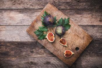 Figs on chopping board and wooden table. Autumn season food photo