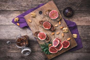 Sliced figs on bread with jam and nuts in rustic style. Autumn season food photo
