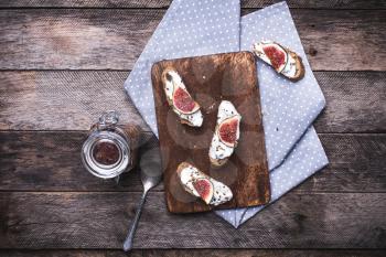 Bruschetta with cream cheese and figs on chopping board in rustic style. Breakfast, lunch food photo