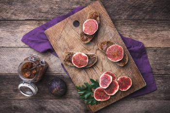 Sliced figs and bread with jam on choppingboard in rustic style. Autumn season food photo