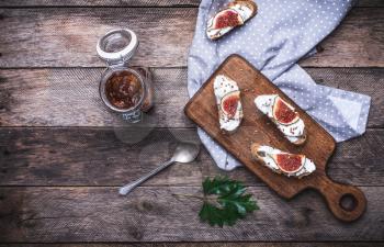 Sliced figs, jam and Bruschetta on choppingboard in rustic style. Breakfast, lunch food photo