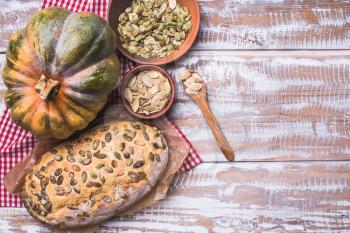 Newly baked bread with seeds and pumpkin on wooden table. Rustic style