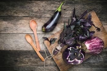 Aubergines with basil and two spoon on wood boards. Rustic style and autumn food photo