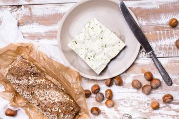 cheese with dill and bread huzelnuts on wooden board in rustic style