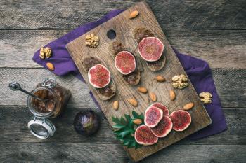 Sliced figs, nuts and bread with jam on wooden choppingboard in rustic style. Autumn season food photo