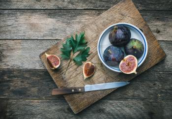 Cut Figs and knife on chopping board in rustic style. Autumn season food photo