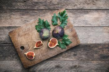 Cut Figs on chopping board and wooden table. Autumn season food photo