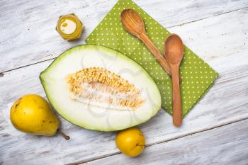 Melon with honey and two yellow pears on wood in rustic style