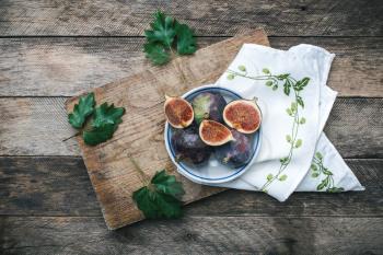 Ripe figs on chopping board and napkin and wooden table. Autumn season food photo