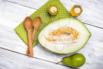 Ripe melon spoons honey and pear on white wood in rustic style